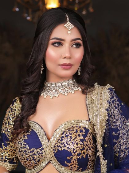 A beautiful engagement or reception look in a royal blue and gold lehenga. The makeup features a classic brown smokey eye and a flawless matte base.