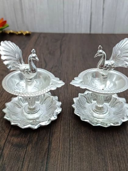 This pair of two-tiered peacock diyas is perfect for creating a layered light effect. Made from German silver, they are both functional and highly decorative.