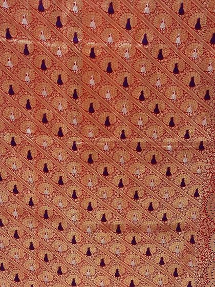 A detail shot of a rich, burnt orange Banarasi textile with intricate peacock motifs. This fabric was chosen for the mother of the bride as part of a royal-themed wedding wardrobe.
