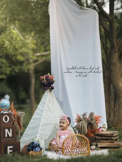The birthday girl sitting happily in her outdoor boho wonderland. The combination of natural elements and curated props makes for a beautiful first birthday memory.
