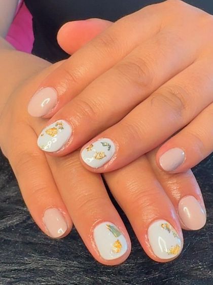 A delicate look on short nails with a mix of nude and white polish, accented with gold foil.