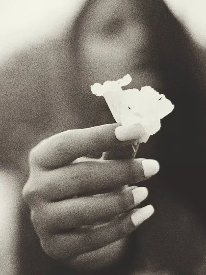 A grainy, black and white version of the flower portrait, giving it a timeless, film-like quality. The focus remains on the hand and the flower, emphasizing the theme of empowerment and the simple, significant details of a moment.