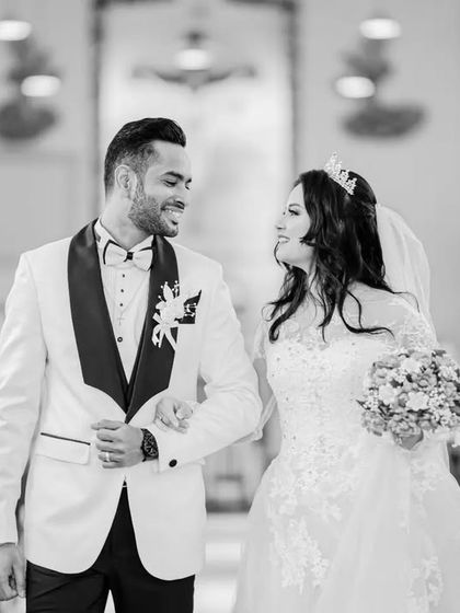 A classic black and white photo of the couple walking down the church aisle, arm in arm. This is a timeless shot from a Christian wedding ceremony.