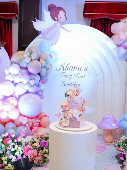 The complete cake display for Ahana's Fairy First Birthday, featuring a gorgeous cake on a pedestal in front of an inflatable arch backdrop.