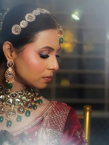 A close-up profile shot highlighting the glittery eye makeup and the intricate details of her kundan and emerald jewelry.