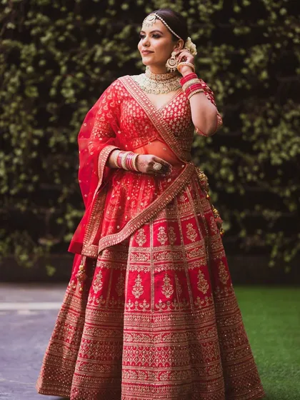 A full-length shot of the bride, showing off her stunning red lehenga. The makeup is elegant and comfortable, allowing her to shine effortlessly.