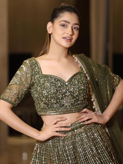 A confident pose in our olive green and gold lehenga. The detailed craftsmanship and rich color palette make this a standout piece in our collection.