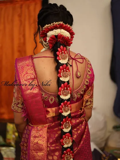 An elaborate Poola Jada with fresh jasmine, red flowers, and traditional hair ornaments. This hairstyle is a work of art and a key part of the bridal look.