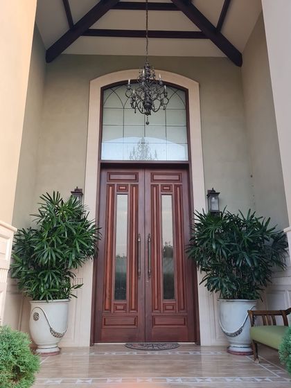 The grand entrance features a high archway, a classic chandelier, and stately double wooden doors, creating a breathtaking first impression that speaks of timeless elegance.