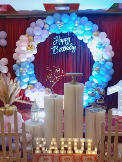 A first birthday celebration at home with a red curtain backdrop. The blue, white, and gold balloon ring stands out beautifully.