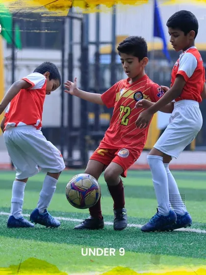 An intense battle for the ball between three U9 players during a friendly match.