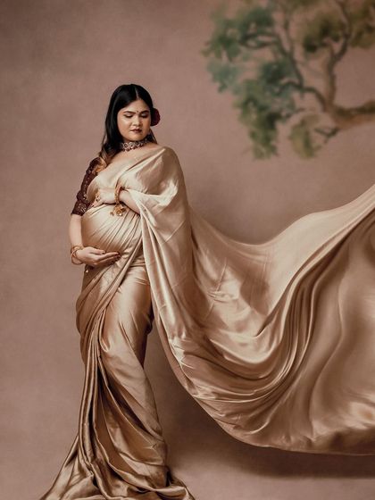 The flowing fabric of the golden saree adds a sense of movement and drama to this stunning portrait. The mom-to-be looks absolutely ethereal.