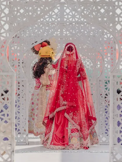 A beautiful shot of the bride's entry, showcasing the full silhouette of her stunning red lehenga and the way the double dupatta is draped.