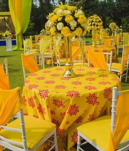 A vibrant table setup for a Haldi lunch. I used printed yellow tablecloths, matching chair drapes, and a tall floral centerpiece to continue the festive theme throughout the dining area.