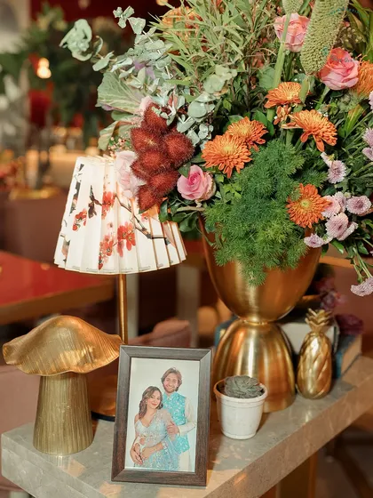 A tablescape detail, combining a personal photo of the couple with a quirky mushroom lamp and a lush floral arrangement.