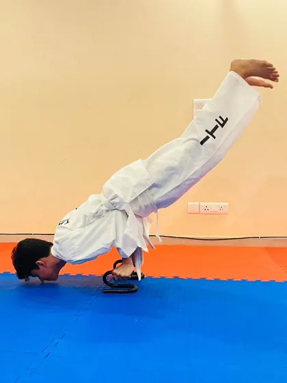 Here, a student performs a challenging push up variation on grips, a drill designed to build exceptional wrist and upper body strength for powerful punches.