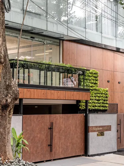 The facade of the Meghana Foods corporate office in Koramangala, designed to command attention. We blended modern wood-finish panels, a structural glass front, and an integrated vertical garden to create a sophisticated and nature-infused commercial exterior.