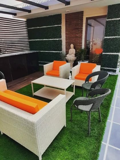 This terrace combines comfortable wicker seating with vertical garden walls and a Buddha statue, creating a space that is both stylish and serene.