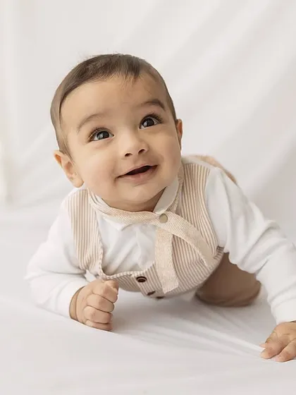 A curious baby looking up, captured in a bright, minimalist setting.