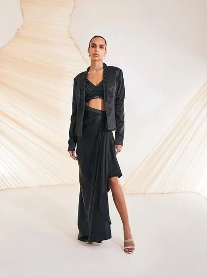 The Debro Jacket Set is an alluring amalgamation of urban design and Indian adornments, featuring a rich satin blazer with a draped skirt.