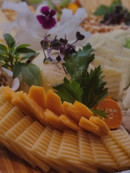 A detailed shot of intricately sliced cheeses, garnished with fresh herbs and edible flowers. This highlights the meticulous attention to detail that goes into the presentation of every board.