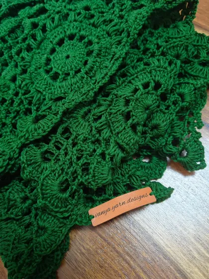 The final touch that makes every creation officially mine. I love adding these custom "vanya yarn designs" leather tags to my finished pieces. This close-up shows the intricate stitch work of the green lace top.
