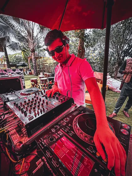 When the sun is your spotlight. DJing under a red umbrella at a daytime garden party, keeping the vibes cool.
