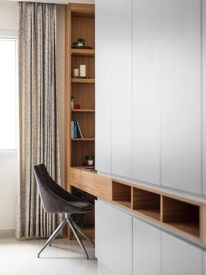 This is not a typical wardrobe. The hinged doors extend all the way to the ceiling, creating an expansive, seamless look and eliminating a separate loft. The design also integrates a study table and open shelving.