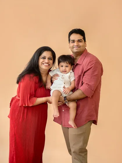 A simple and sweet family portrait against a neutral backdrop. The coordinated outfits in warm tones create a harmonious and inviting feel.