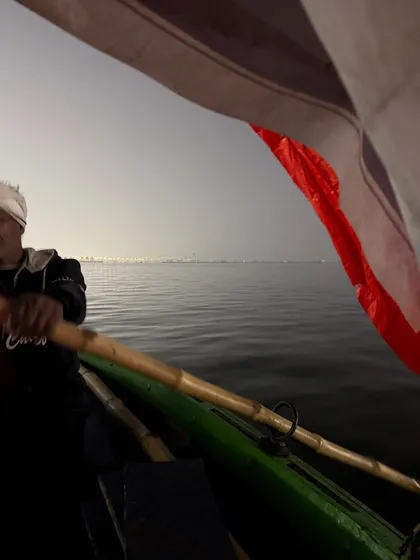 A boat ride on the Sangam at dusk during the Mahakumbh. The vastness of the water and the distant lights of the camp create a surreal and meditative atmosphere.
