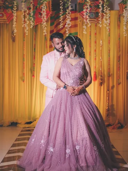 A classic couple portrait from their engagement, posing against a festive yellow backdrop.
