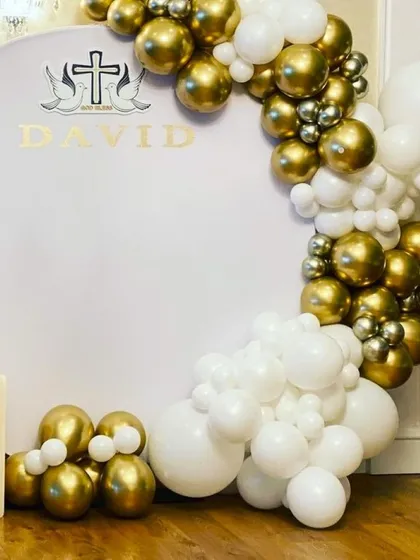A Holy Communion balloon decoration in white, gold, and silver. The personalized backdrop makes it a special setup for the child's big day.