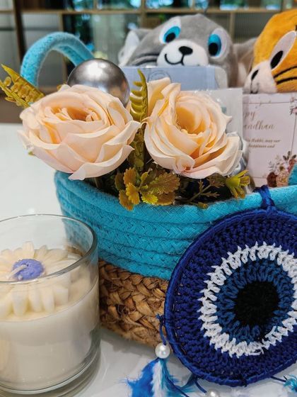 A closer look at the Tom and Jerry themed Rakhi hamper. The bright blue rope basket is filled with soft toys, a daisy-shaped candle, and an evil eye charm, making it a playful and cute gift for a younger sibling.