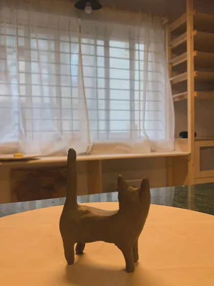 The back of the ceramic cat 'Luna,' showing her curious, upright tail.