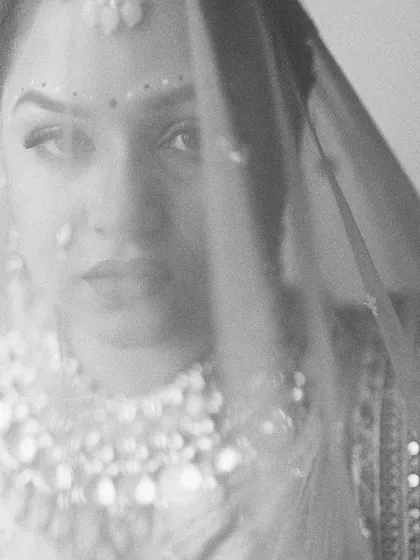 A grainy, black and white close-up of the bride through her veil. This artistic shot has a mysterious and timeless quality, focusing on the intensity of her gaze.