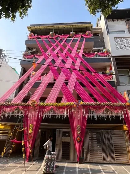 This is an example of a full house exterior decoration to create a festive wedding atmosphere. I used long pink fabric drapes crisscrossing the building's facade, anchored with floral arrangements, to make the home stand out for the pre-wedding functions.