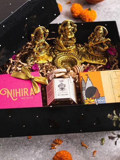 A detailed look inside the "Diya" hamper, revealing the intricate brass idols resting on a bed of natural filler, surrounded by gourmet treats.