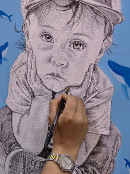 This close-up shows the delicate process of shading a child's face using a ballpoint pen, capturing a soft and emotional expression.