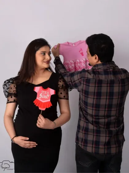 A sweet gender reveal moment. The "It's a Girl!" prop and tiny pink dress add a pop of color and excitement to this minimalist shoot.