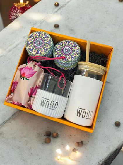 This corporate gift set for 'WORD' features a branded borosilicate glass and sipper, along with decorative tins, presented in a vibrant yellow box. It's a great example of practical and eye-catching branding.