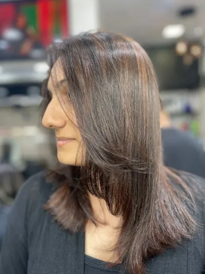 A simple and elegant layered cut on medium-length dark hair, styled straight for a polished finish.