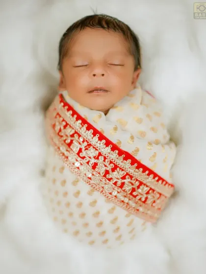 A close-up of the newborn 'Bal Shivaji', peacefully sleeping, wrapped in an elegant embroidered cloth.