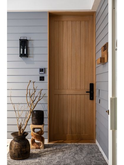 An entryway should be a statement that reflects the soul of the home. This rustic-modern main door, made of natural wood with vertical slats, is paired with shiplap-style wall paneling for a warm and inviting welcome.