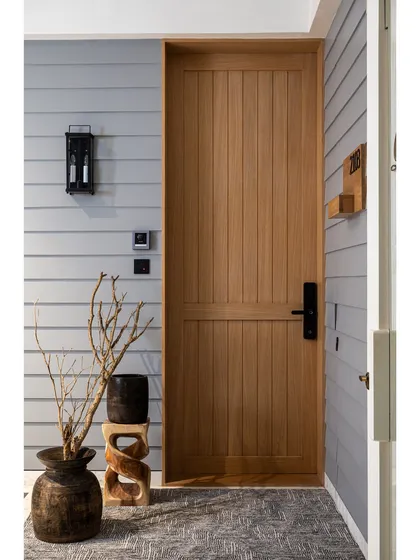 An entryway should be a statement that reflects the soul of the home. This rustic-modern main door, made of natural wood with vertical slats, is paired with shiplap-style wall paneling for a warm and inviting welcome.