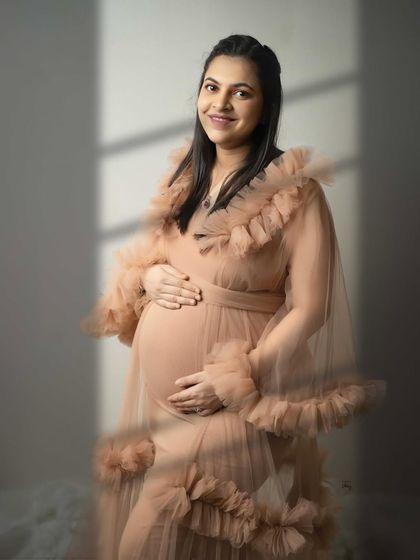 A happy smile from the mama-to-be. The soft light and the delicate ruffles of her gown create a portrait that is both joyful and elegant.