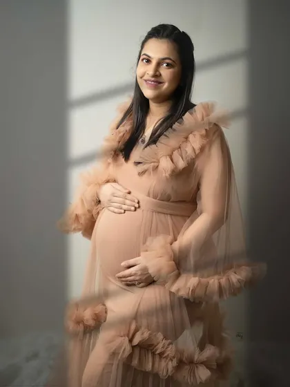 A happy smile from the mama-to-be. The soft light and the delicate ruffles of her gown create a portrait that is both joyful and elegant.