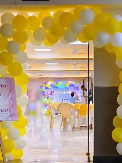 A yellow and white balloon arch at the entrance of a party, creating a bright and cheerful welcome for guests.