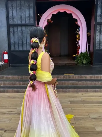 A side angle of a floral bubble braid, showing how the flowers are woven into the hair. This style adds a touch of natural beauty to the Mehendi look.
