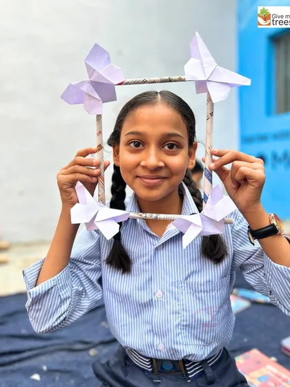 A close-up of a student with her beautiful, handcrafted butterfly frame. The workshop teaches them to see the artistic potential in simple, natural forms.
