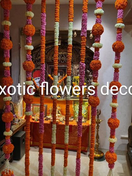 Traditional floral strings, or 'torans', made from marigolds and other flowers, create a festive curtain in front of a home temple, adding color and fragrance.